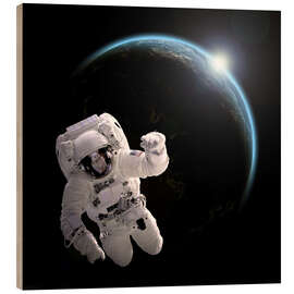 Wood print Astronaut floating in space as the sun rises on to Earth-like planet.