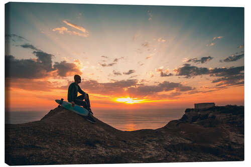 Tableau sur toile Jeune homme et son skate regardant le coucher du soleil