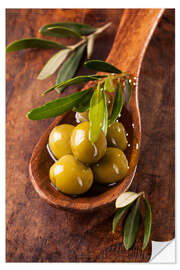 Sisustustarra Spoon with green olives on a wooden table