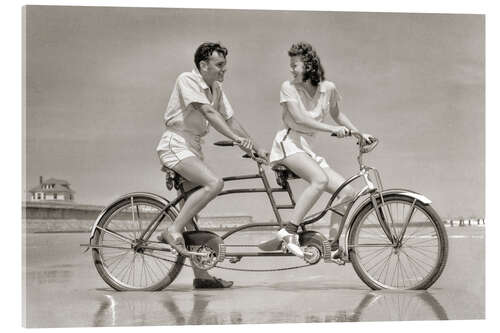 Quadro em acrílico Young couple riding a tandem bike on the beach, 1940s