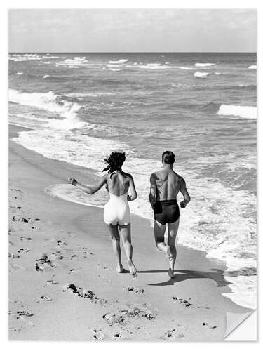 Sticker mural Couple wearing jogging at edge of ocean beach, 1930's